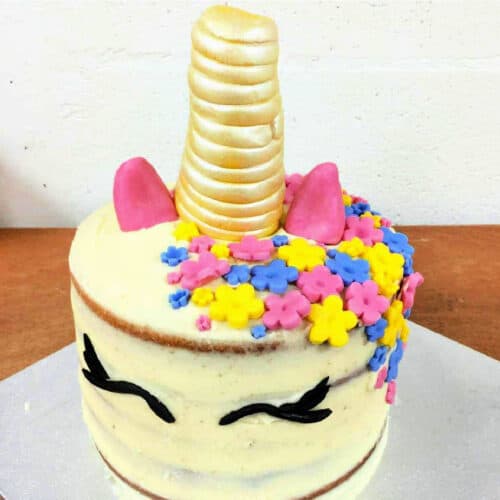 Simple unicorn cake with fondant decoration and gold-sprayed horn.