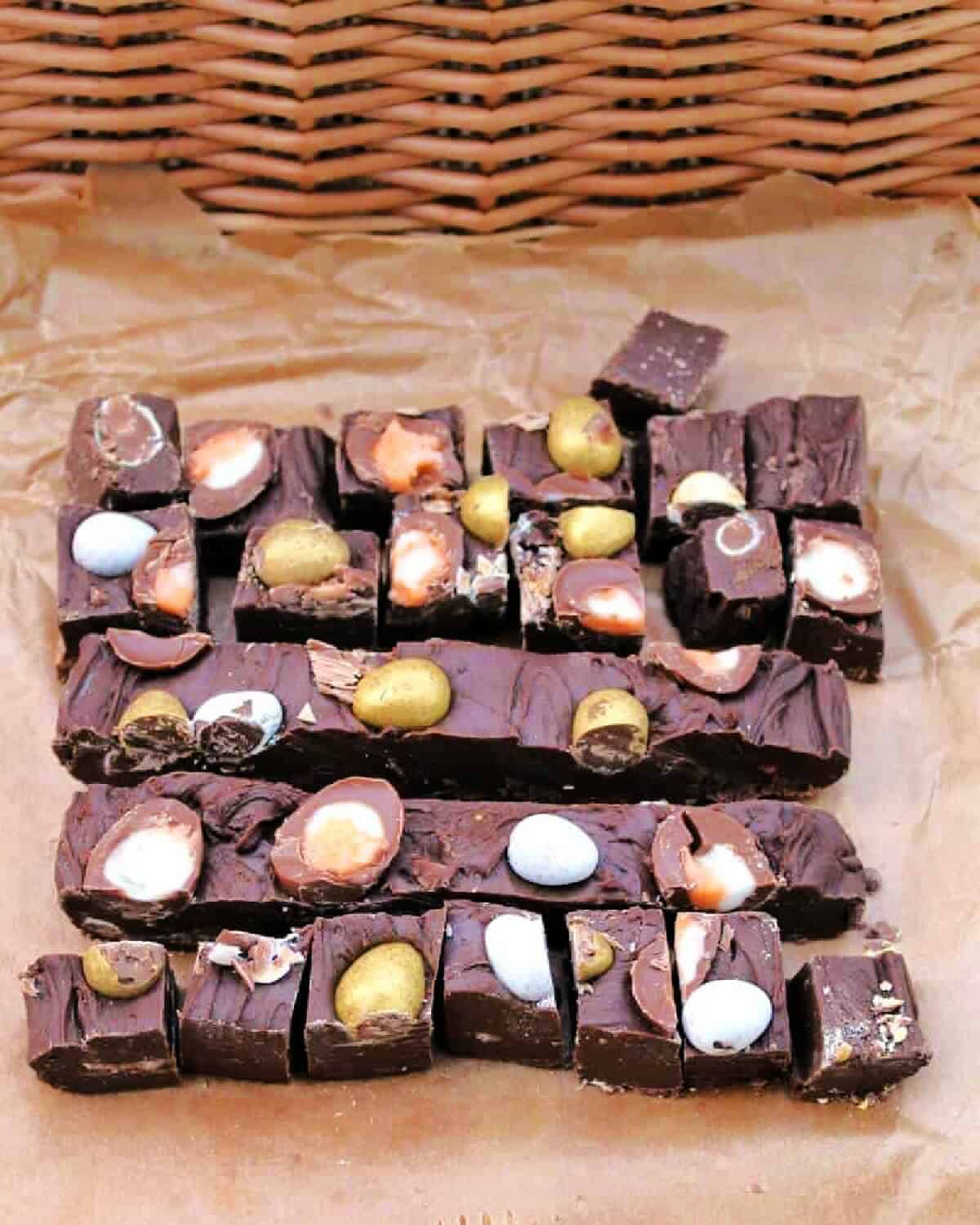 Chunks of chocolate fudge topped with mini Easter eggs on baking paper.