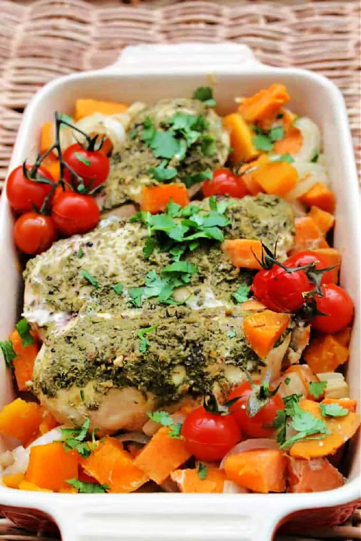 Serving dish of chicken with pesto and vegetables.