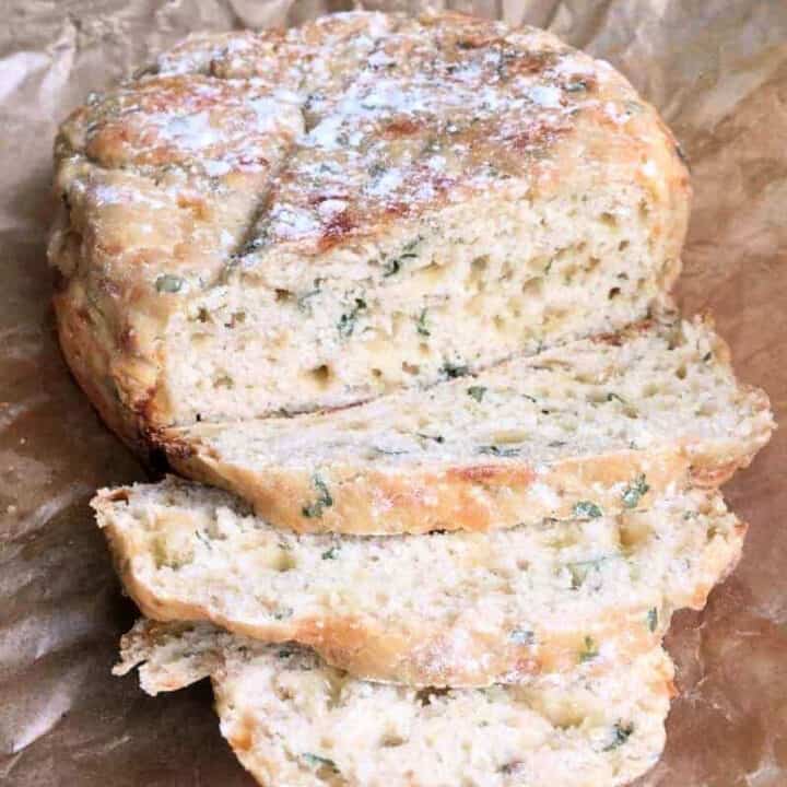 Close up of sliced cheesy bread with herbs visible inside.