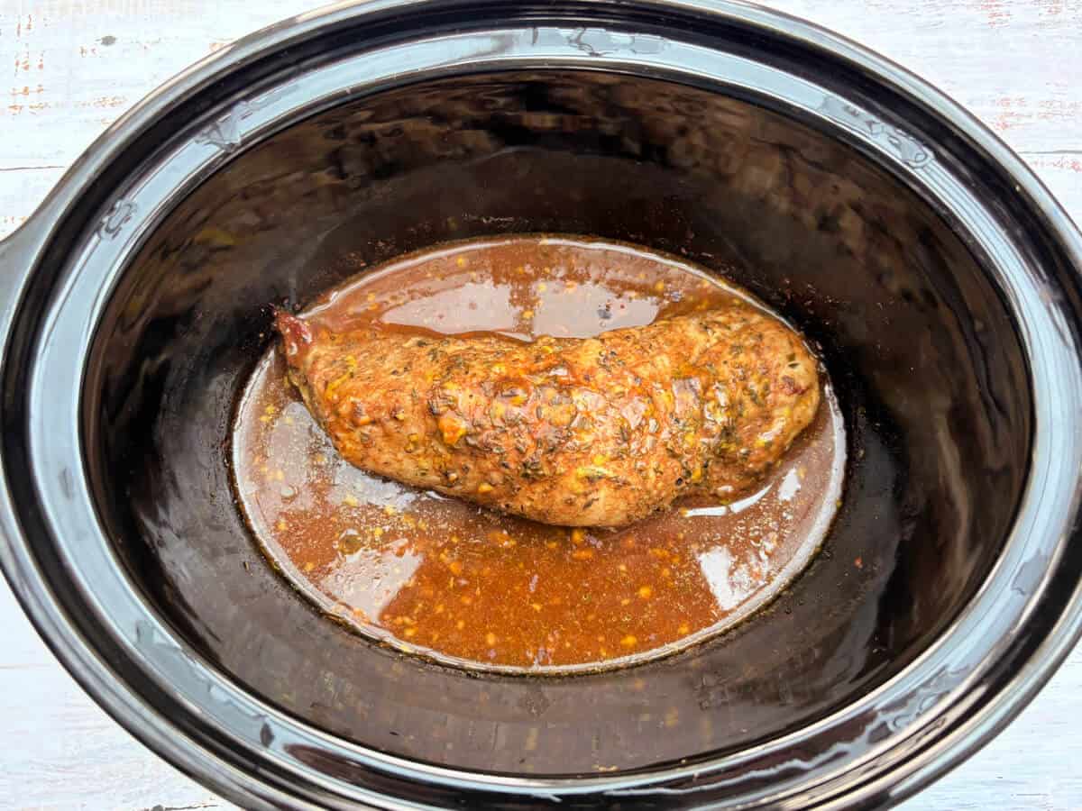 Cooked pork tenderloin in black pot.