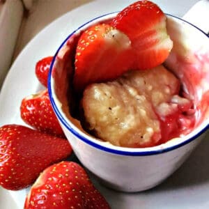 White cake with mug cake inside and sliced strawberries.