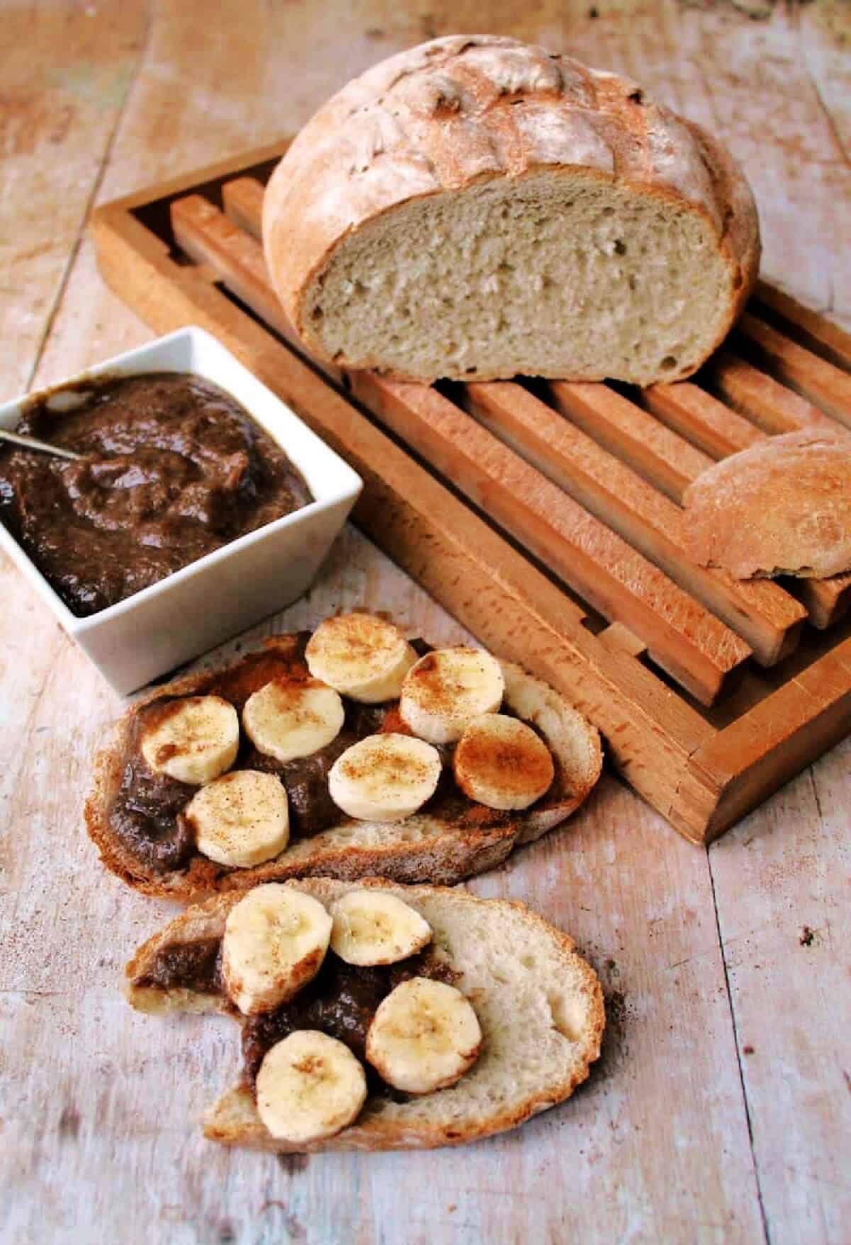 Loaf of bread with slices cut spread with banana butter topped with fresh banana slices.