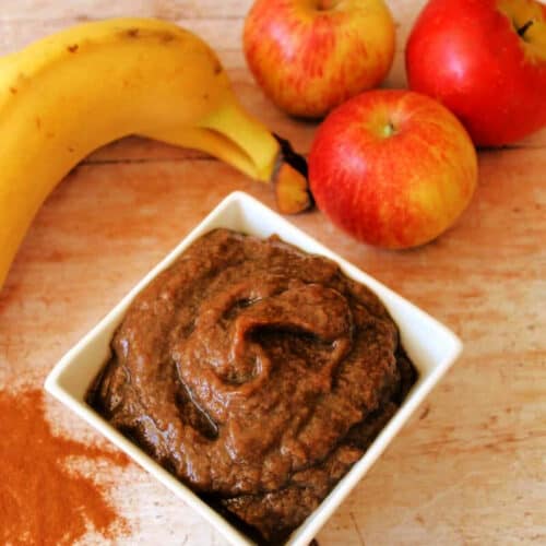 Pot of fruit butter with fruit in background.