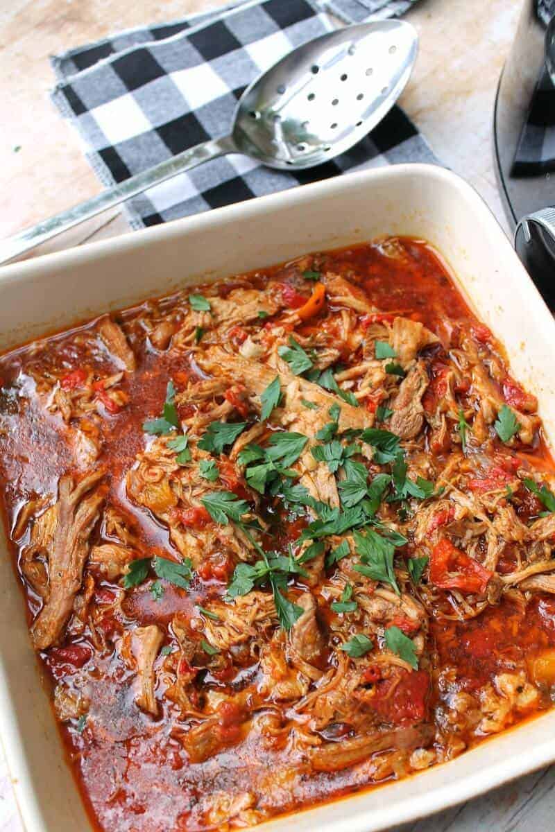 Paprika pork goulash served in an earthenware dish with a serving spoon to the side.