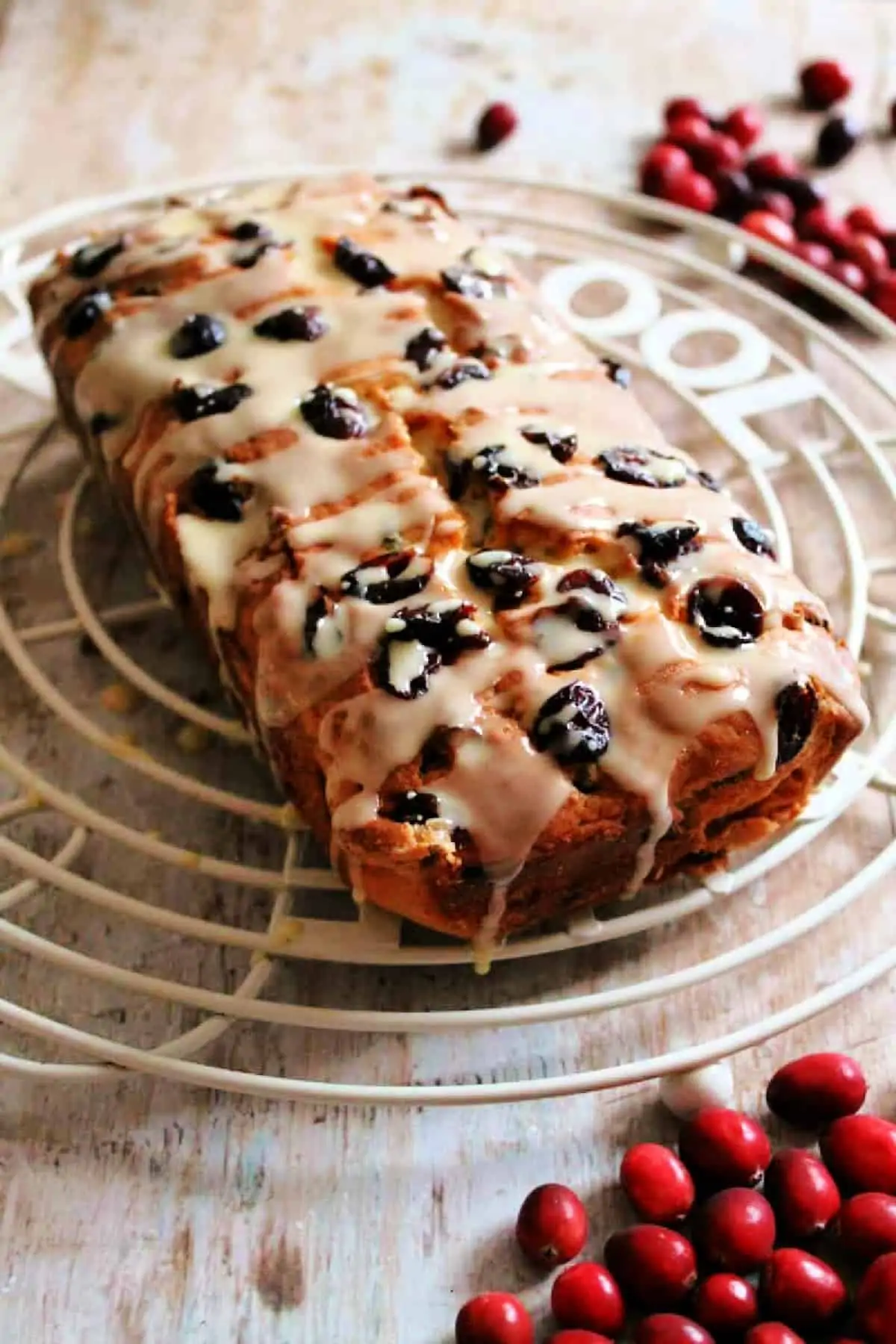 Loaf cake with cranberries on a cooling rack.