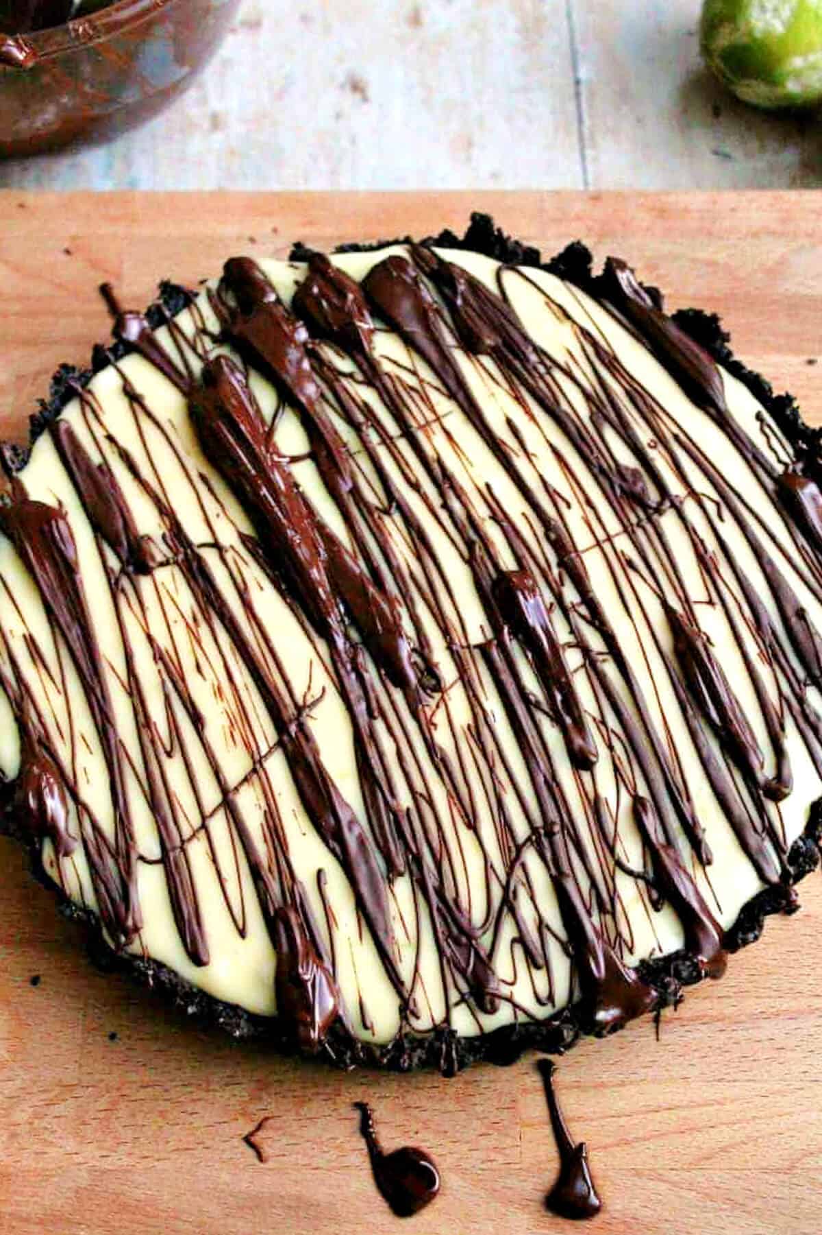 White chocolate tart with chocolate drizzle on a board.