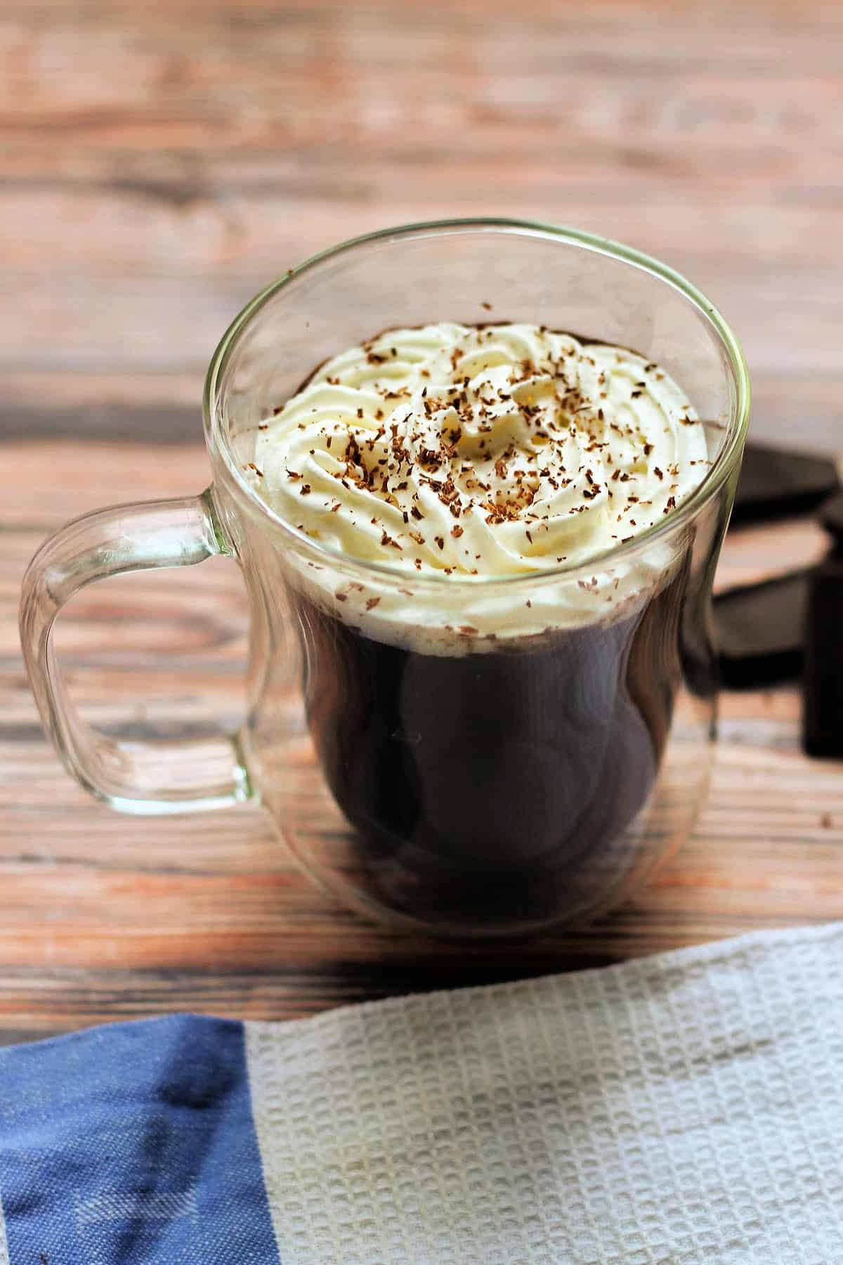 A cup of hot chocolate with cream and chocolate shavings on top.