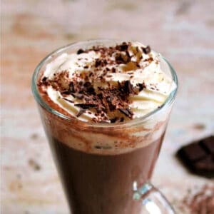 Cup of hot chocolate topped with whipped cream and chocolate shavings.