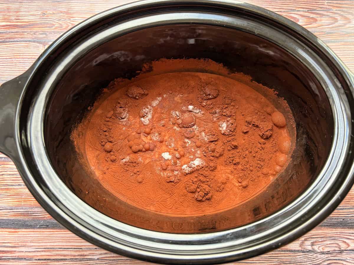 Milk and cocoa powder in slow cooker pot.