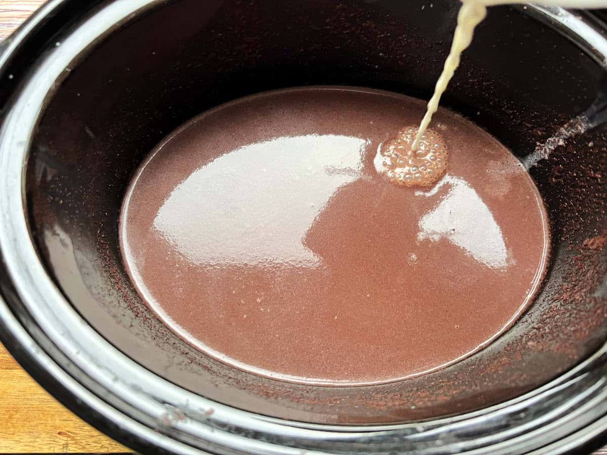 Cornflour paste being poured into slow cooker containing hot chocolate.