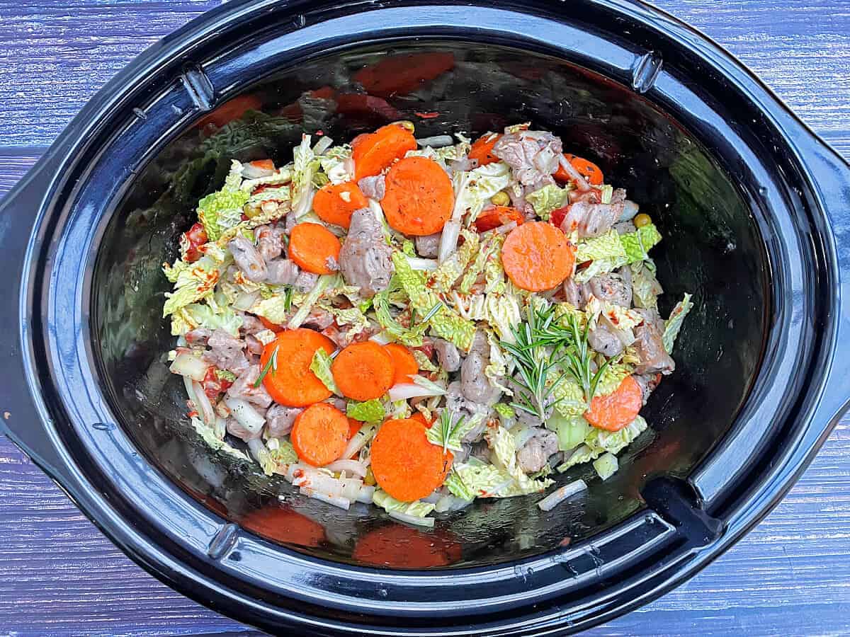 Lamb casserole ingredients in slow cooker pot, ready to cook.