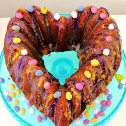 Heart-shaped bundt cake with pastel mini eggs.