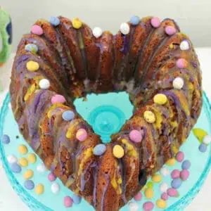 Heart-shaped Mini egg cake with mini eggs on a blue cake stand.