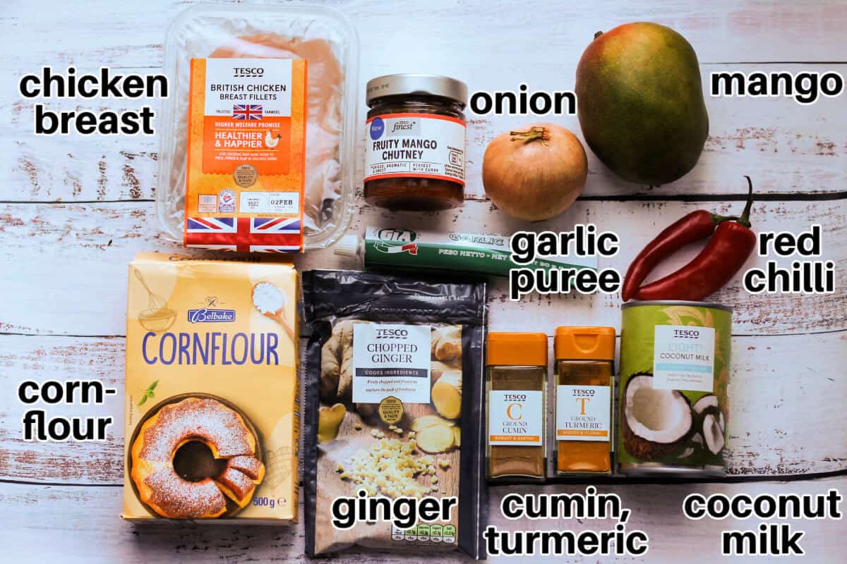 Mango chicken ingredients with text labels, on white wooden table.