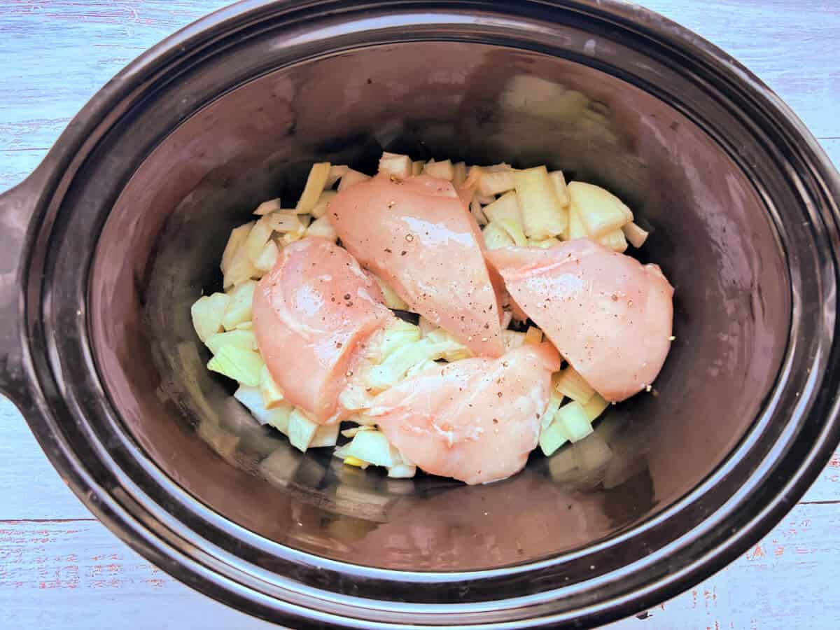 Chicken and onion in slow cooker pot.