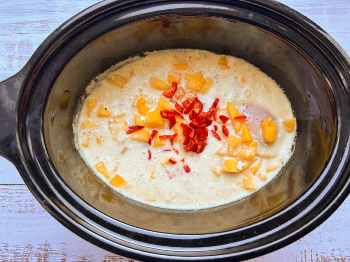 Chicken and mango with coconut sauce added, in slow cooker pot.