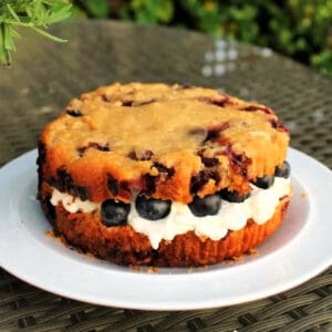 Blueberry scone cake filled with cream on a white plate.