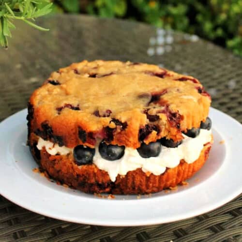 Blueberry scone cake filled with cream on a white plate.