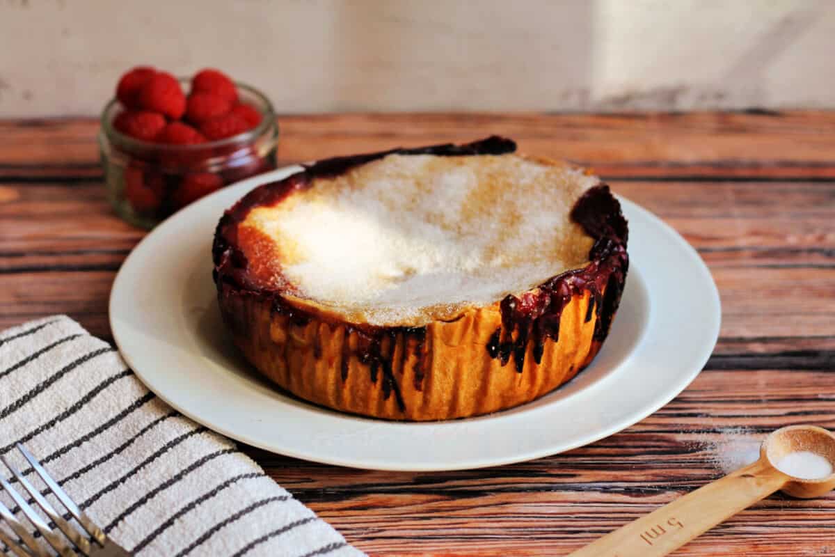 Baked fruit pie on a white plate dusted with sugar.