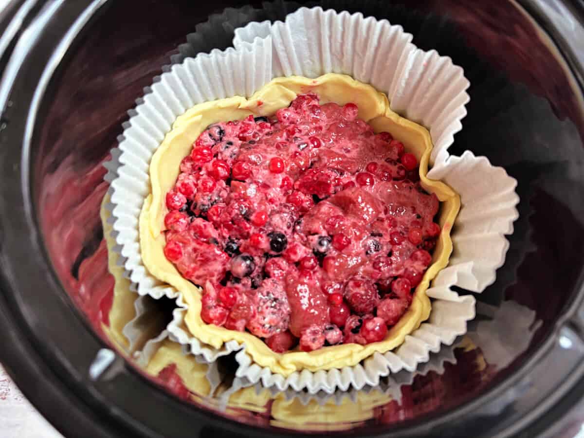 Pie shell filled with berries in slow cooker pot.