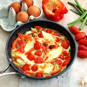 Halloumi red pepper frittata in pan, ingredients around.