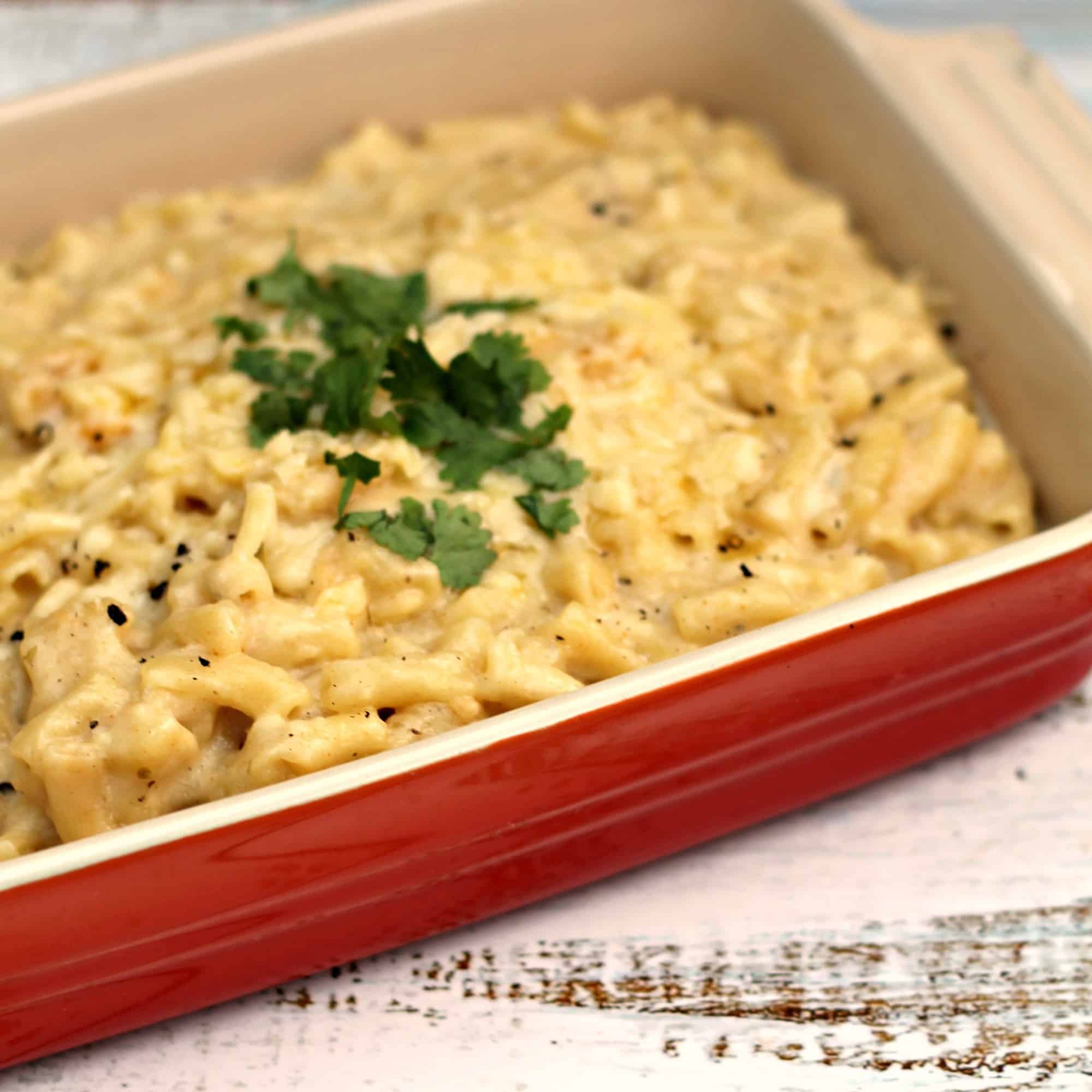 Close up of red ceramic dish filled with macaroni cheese, diagonal view.