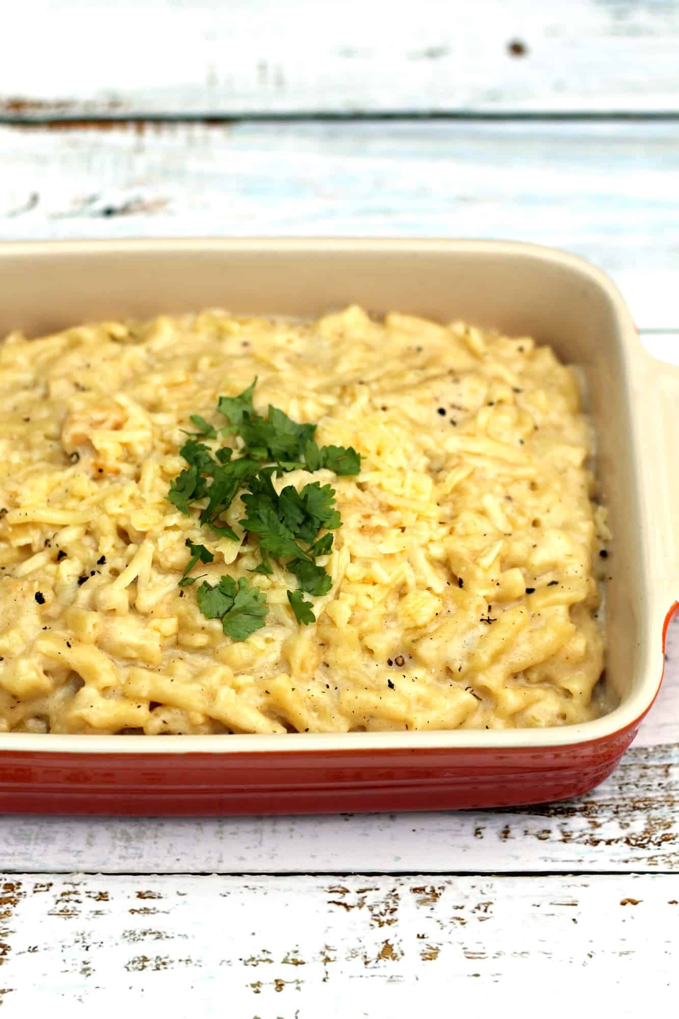 Close up of red ceramic dish filled with macaroni cheese.