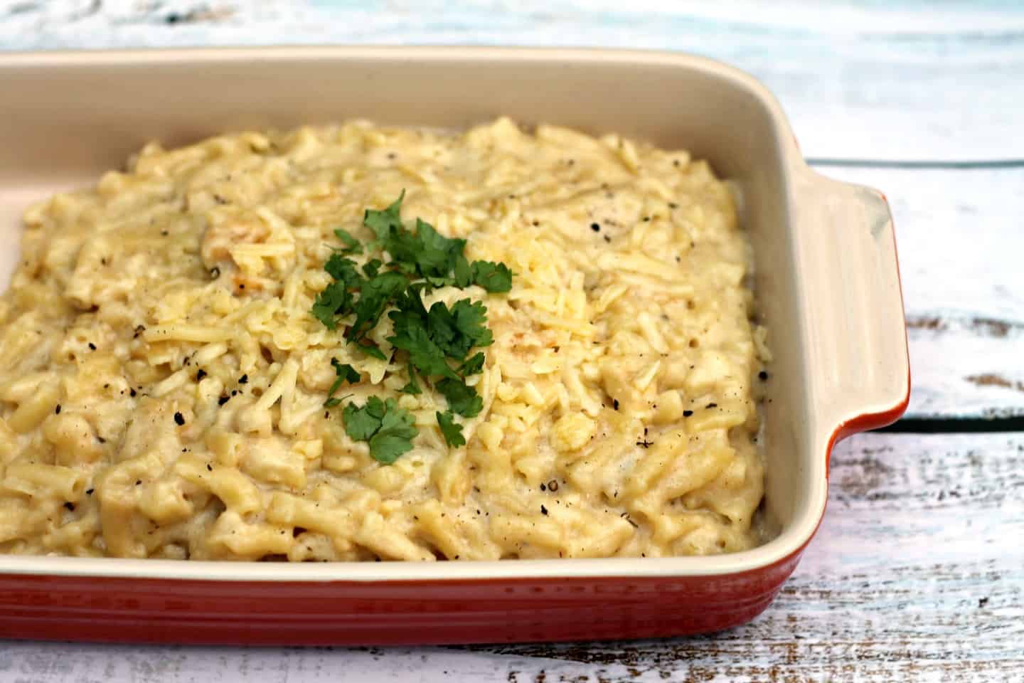 Close up of red ceramic dish filled with macaroni cheese.