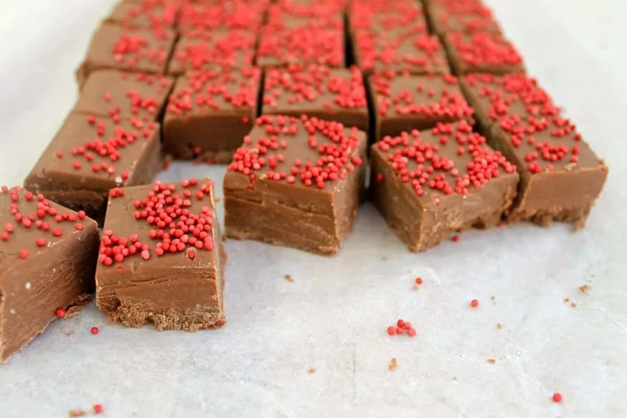 Squares of milk chocolate fudge topped with red sprinkles.