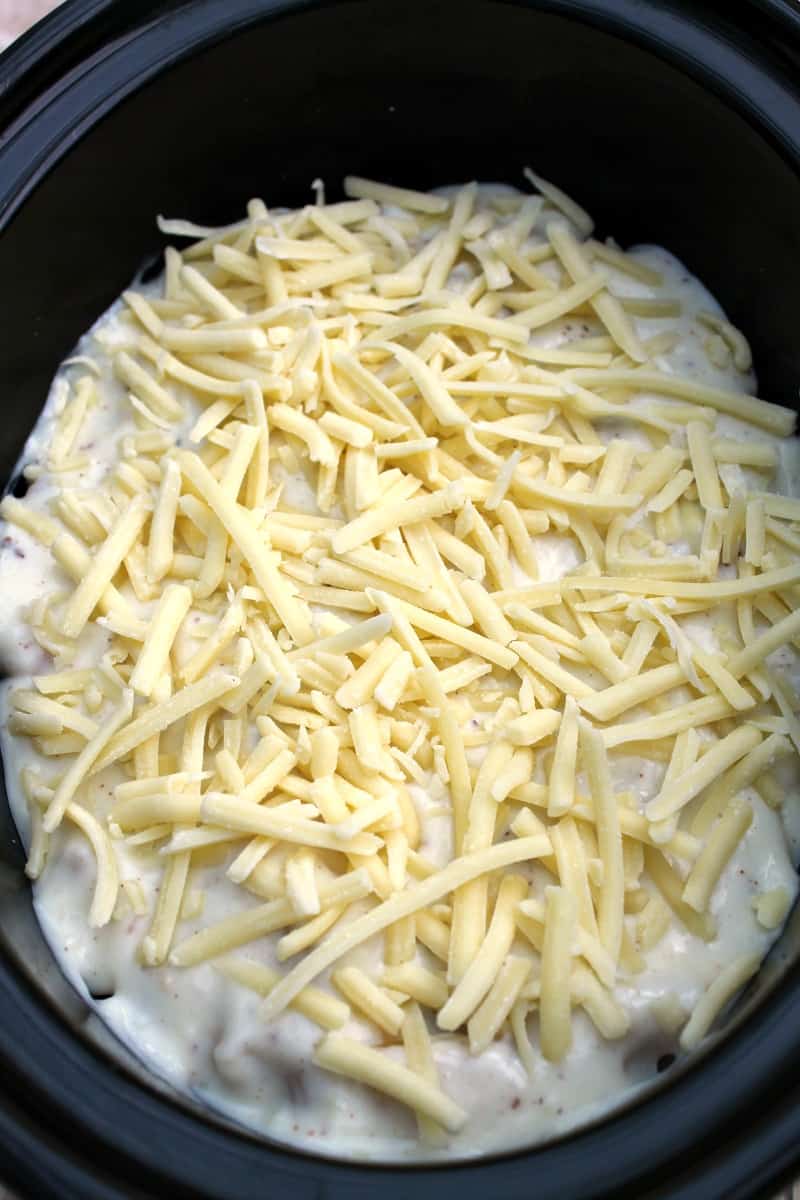 Assembling slow cooker pastitsio - adding the grated cheese on top