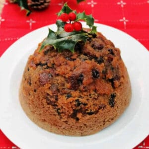 Steamed mincemeat pudding on a white plate, topped with holly.