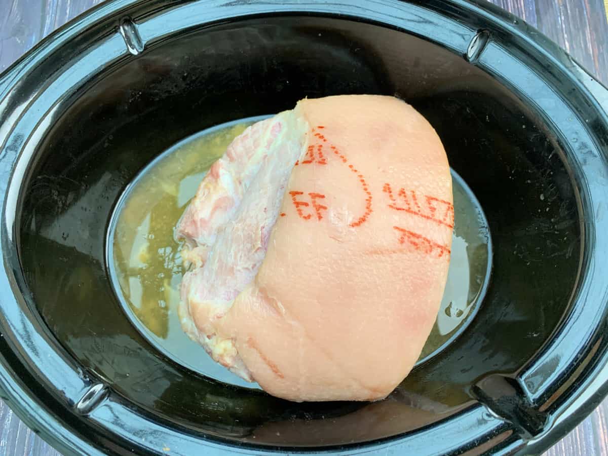 Cooked gammon joint in slow cooker pot.