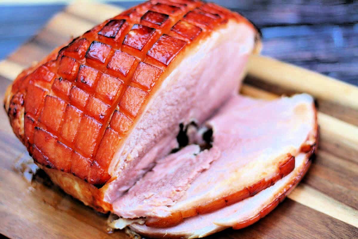 Sliced gammon joint with sticky gammon glaze, on a board.
