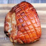 Gammon/ham with scored fat on a wooden board.