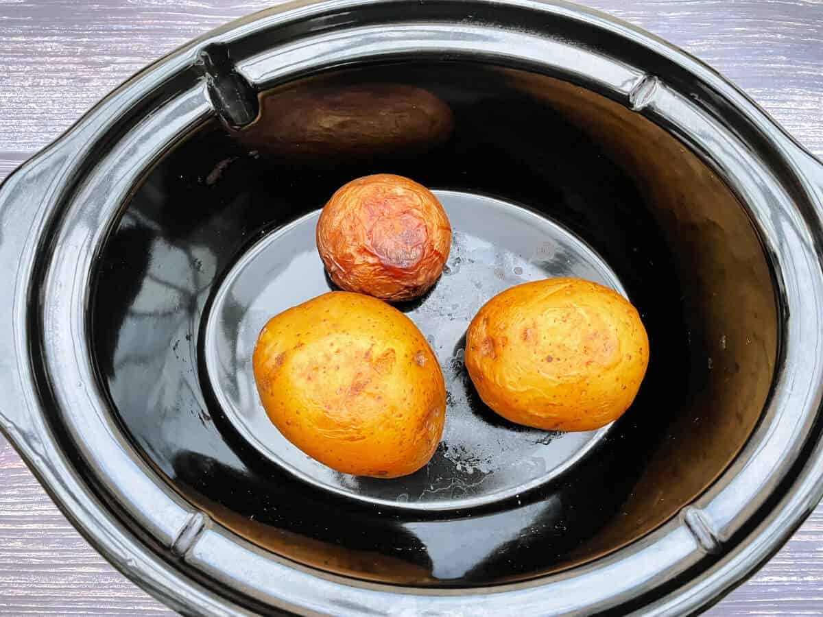 Cooked baked potatoes in a slow cooker pot.