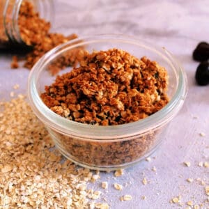 Granola in a small glass pot, ingredients around it.