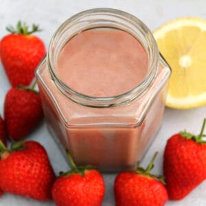 Jar of curd with strawberries around it.