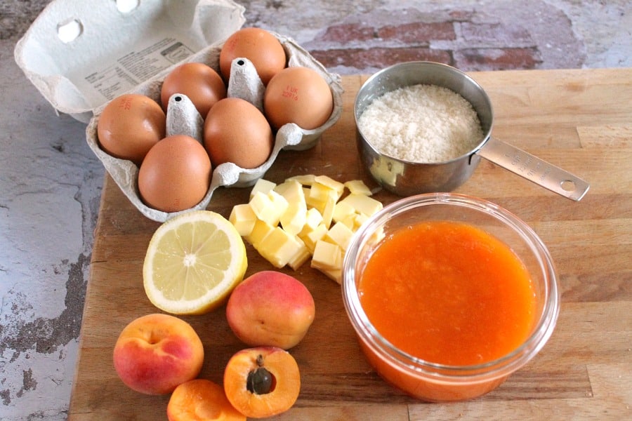 Ingredients on a board - eggs, butter, sugar, apricots, apricot puree, lemon.