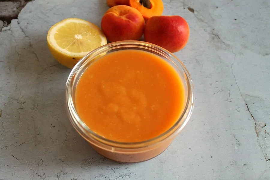 Bowl of apricot curd with lemon and apricots.