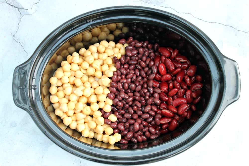 Chickpeas, black beans and red kidney beans in slow cooker pot.