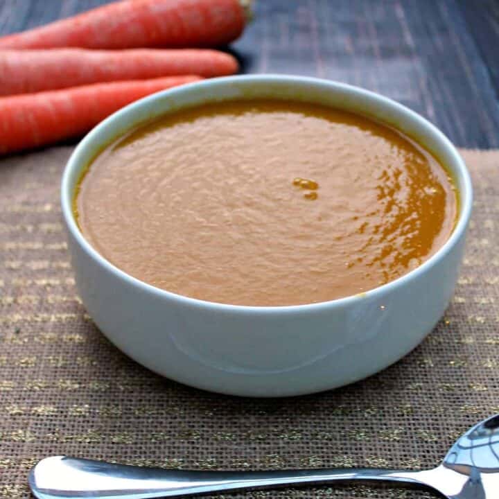 Close up of a bowl of soup on a brown table cloth.