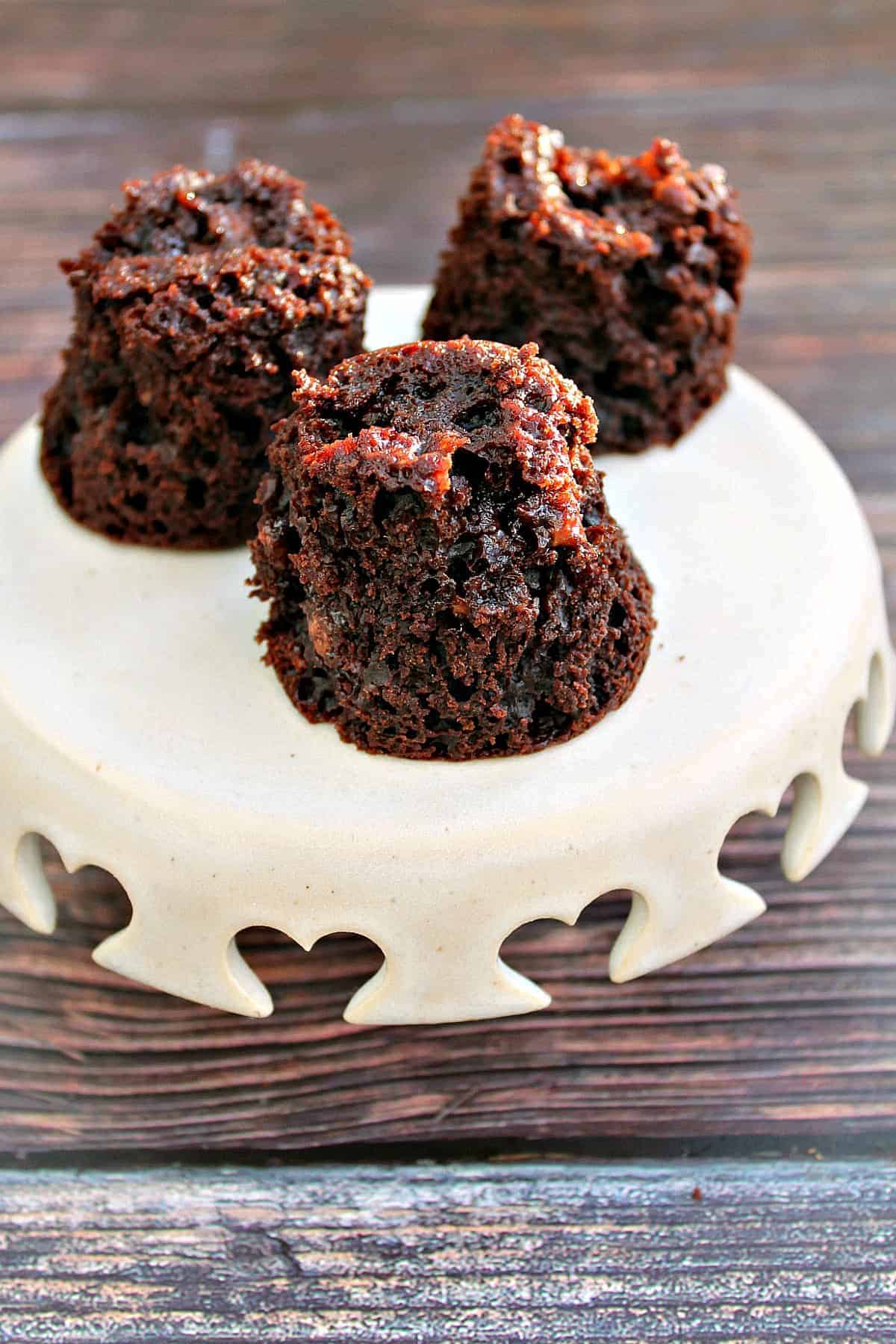 Little chocolate muffins on a small cream cake stand.