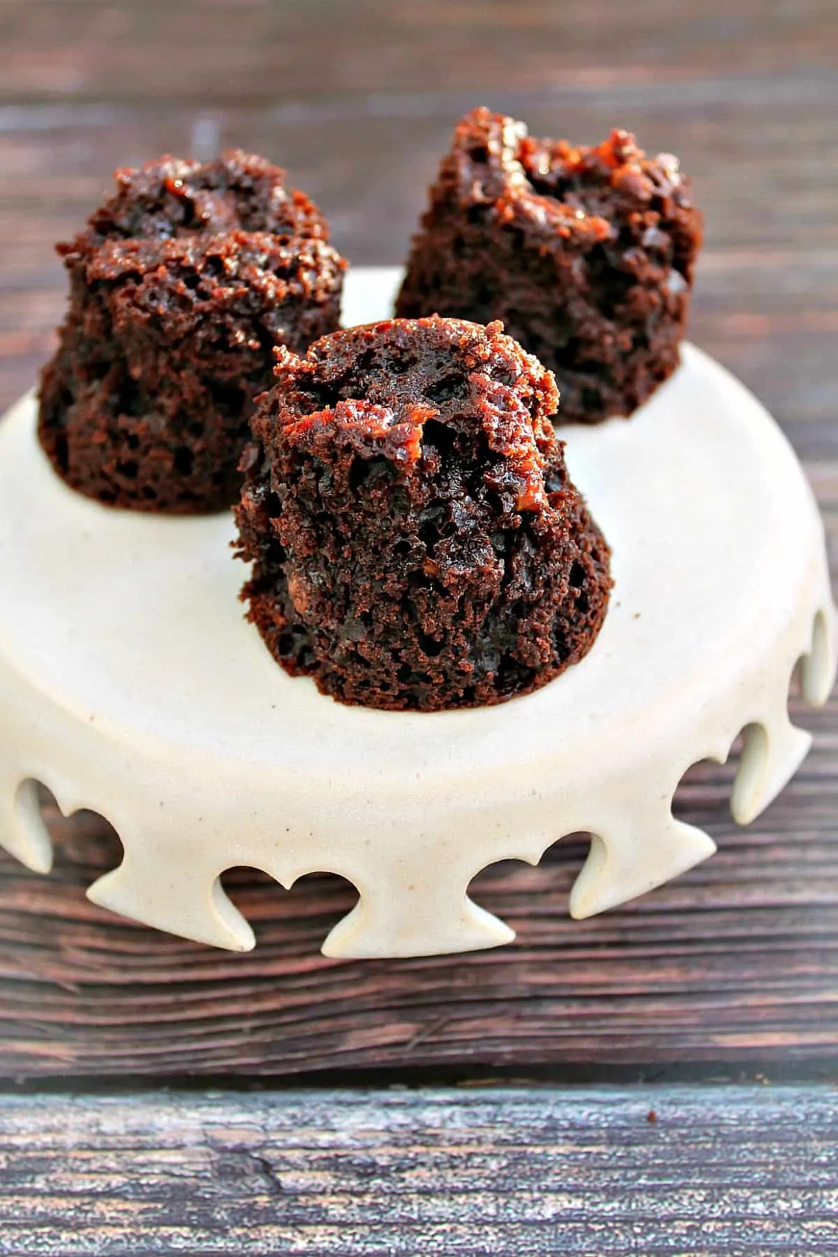 Little chocolate muffins on a small cream cake stand.