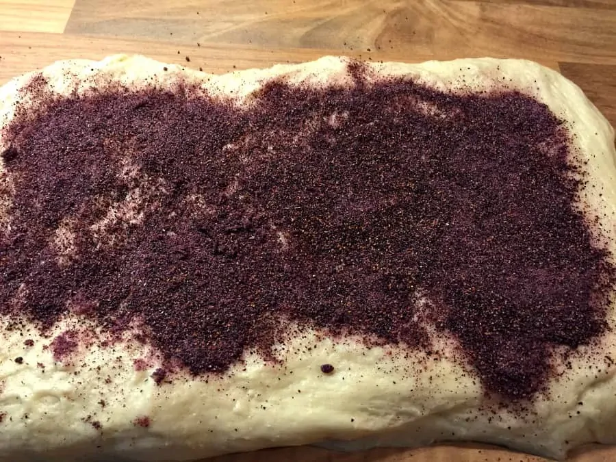 Covering the rolled out dough with blueberry powder.