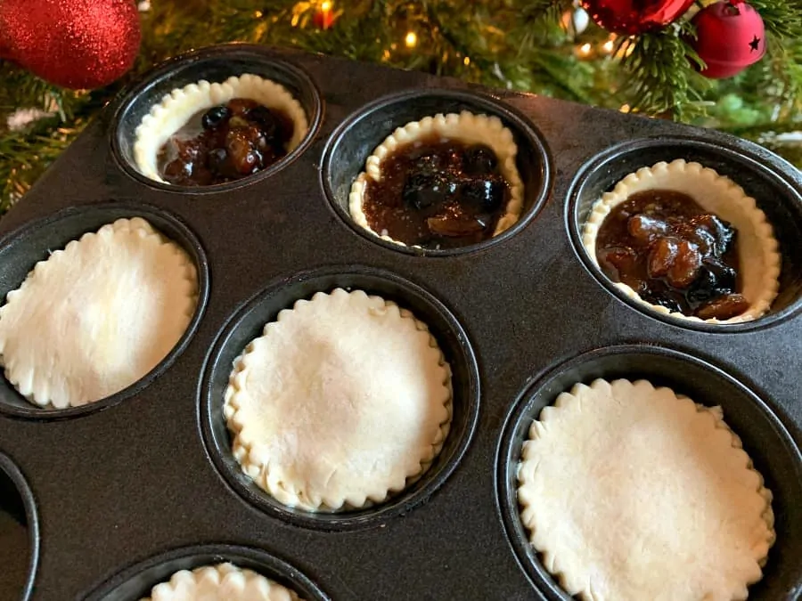Putting lids on mince pies in the tin.