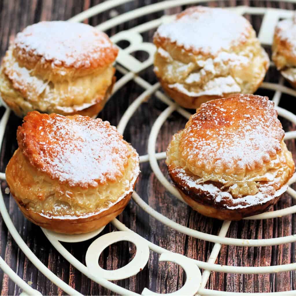 Close up of tall puff pastry mince pies with icing sugar on top.