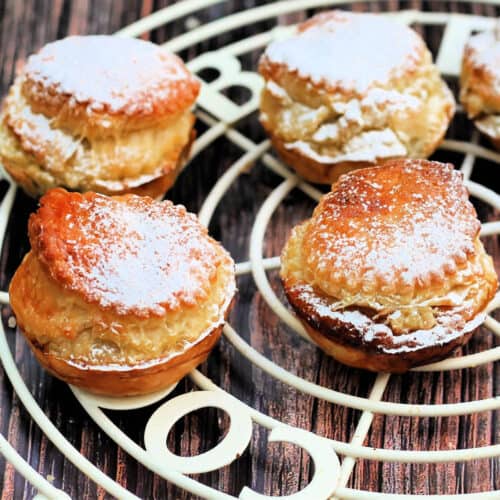 Close up of tall puff pastry mince pies with icing sugar on top.