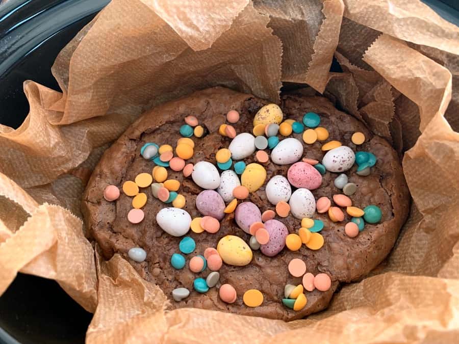 Brownies decorated with mini eggs cooking in slow cooker pot.