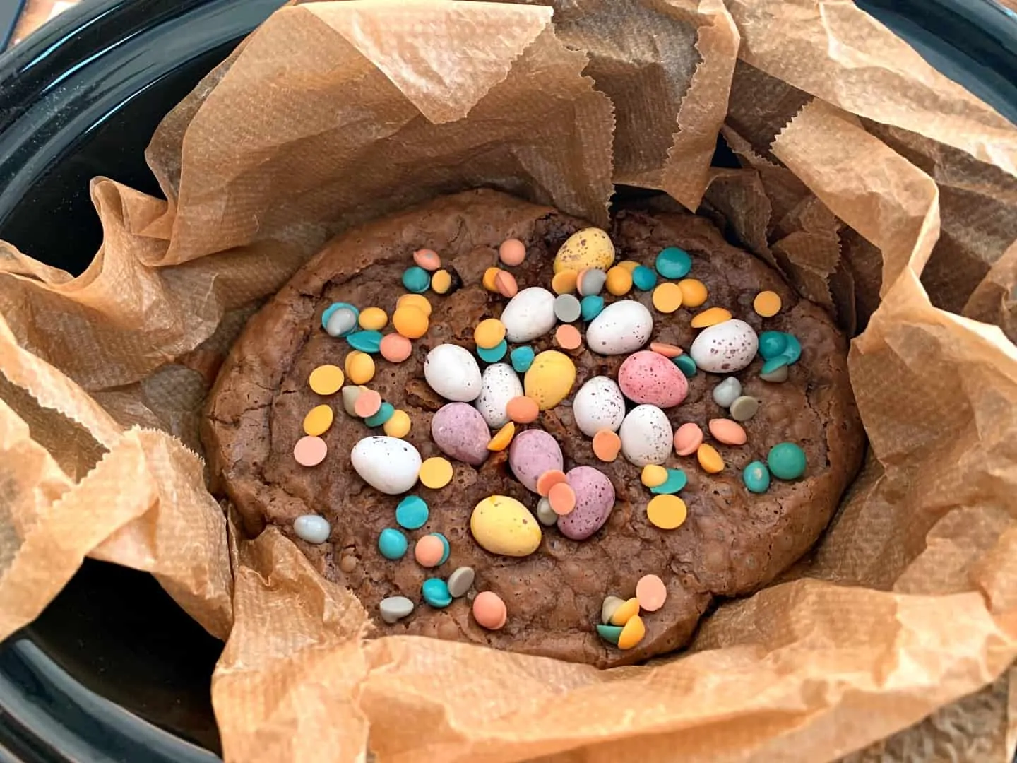 Brownies decorated with mini eggs cooking in slow cooker pot.